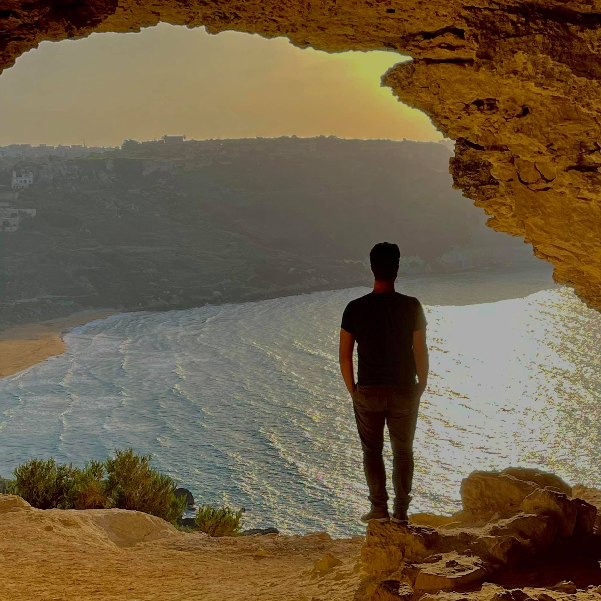 Miguel Defraeye de dos, face à la mer, depuis une ouverture dans la roche